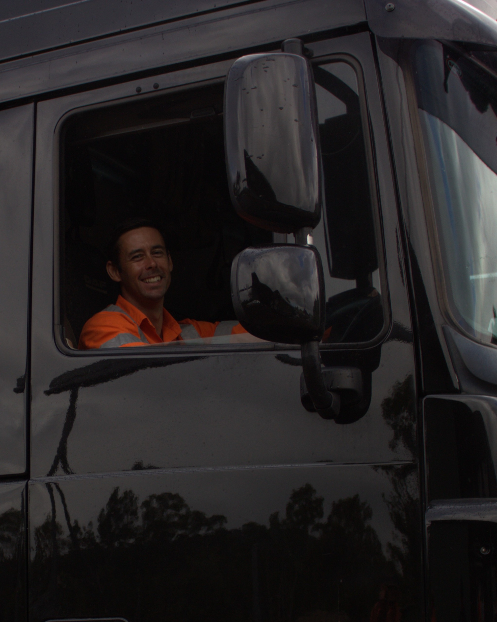 A friendly Nexpave team member in safety gear operating a company truck on site.