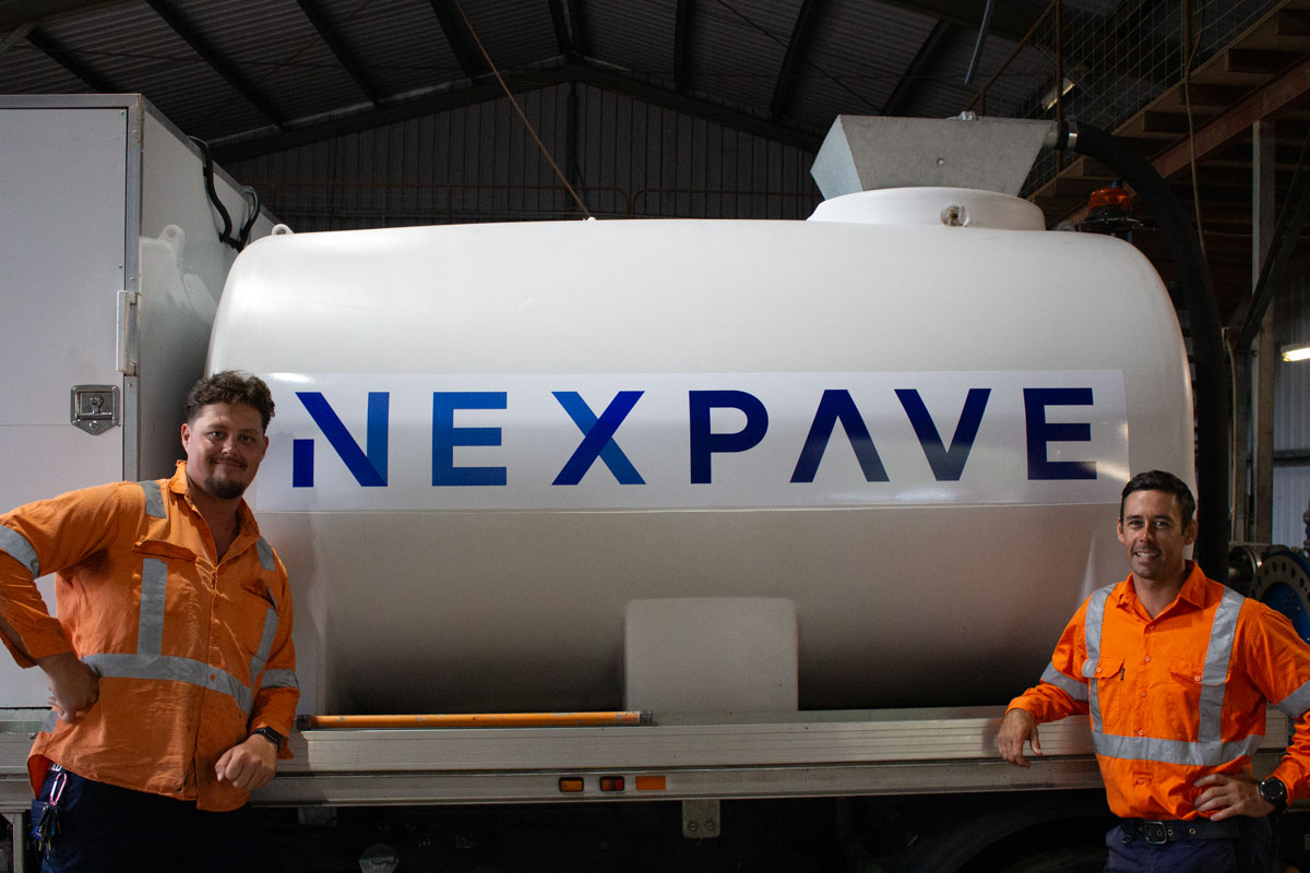 Two smiling Nexpave team members in high-visibility safety gear standing together on a local civil project site.
